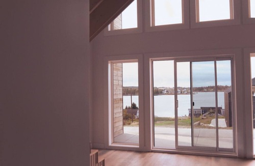 Riverport Cabin | A sanctuary of architectural restraint and unmediated coastal observation, enhanced by illuminated waters.